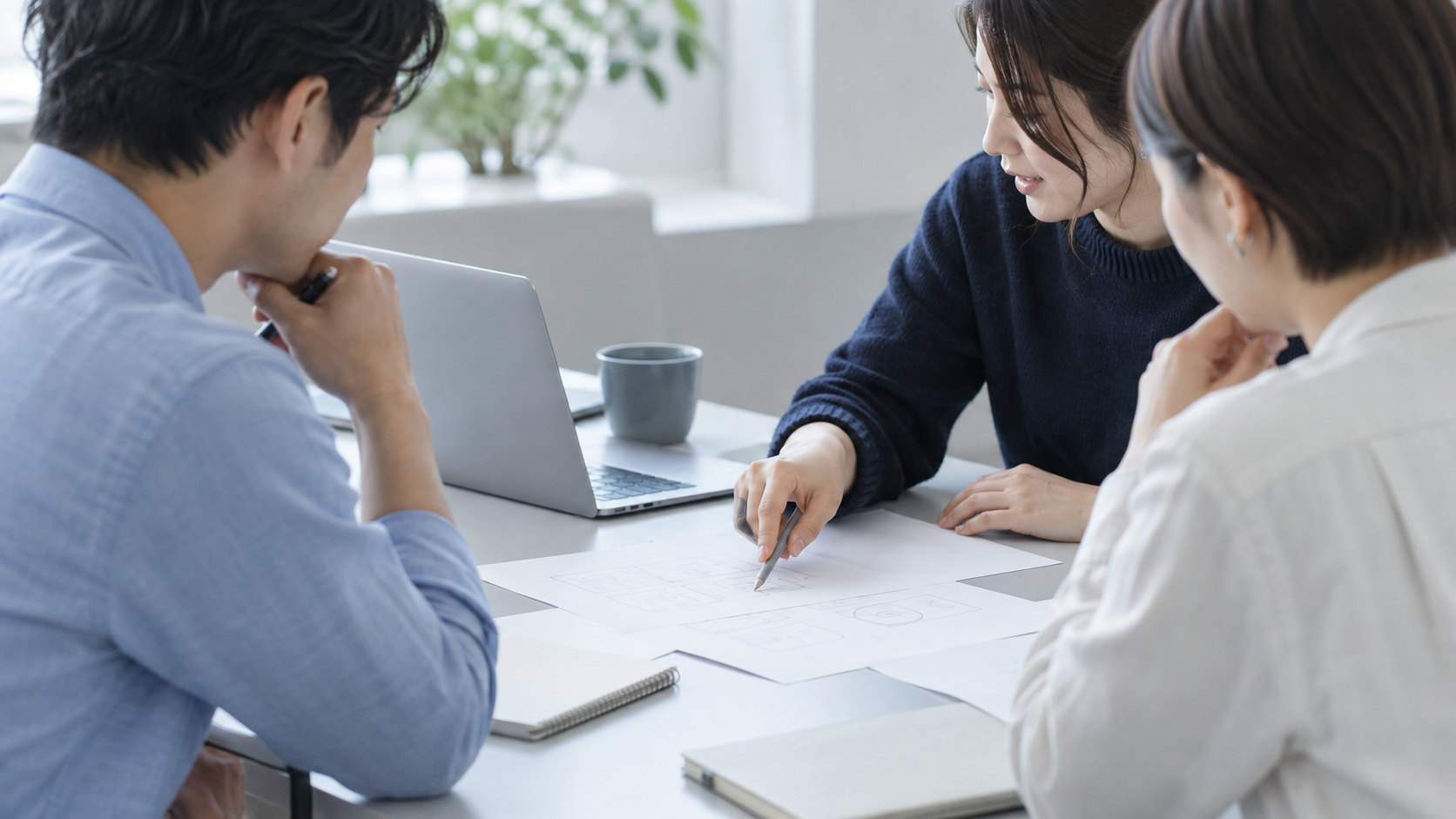 資料を囲み、手元を指し示しながら一緒に考える人々のイメージ